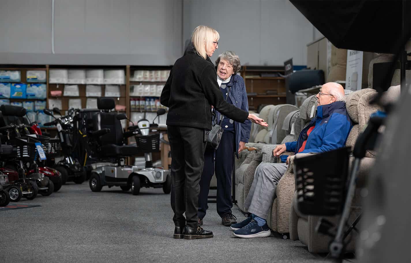 A member of staff at Easi-Way Mobility helping customers choose a recliner chair
